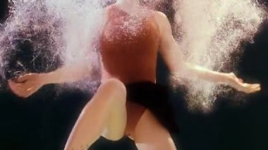 Mayolu ve siyah etekli bir kadın suda yüzüyor, kollarını ve bacaklarını sallıyor.