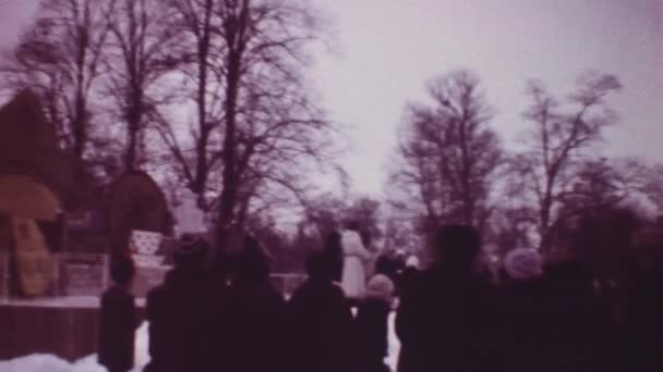 사람들은 공원에서의 겨울 연예 행사에 참가 한다. 무대에서 의상을 입은 남녀들. 차들. 봉분 — 비디오