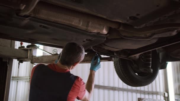 Auto monteur reparaties auto op de lift in het tankstation — Stockvideo