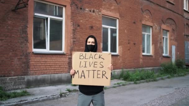 Man met masker staat met kartonnen poster in handen - BLACK LIVES MatTER — Stockvideo