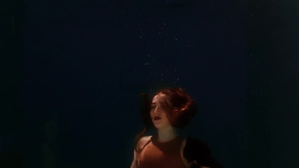 身穿泳衣和黑色裙子的女人在水里游泳，挥动着胳膊和腿 — 图库视频影像