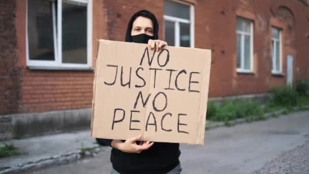 Muž v masce stojí s papírovým plakátem v ruce - BLACK LIVES MATTER — Stock video