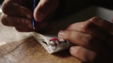 The man puts a notebook on the table and writes something in it with a pen.