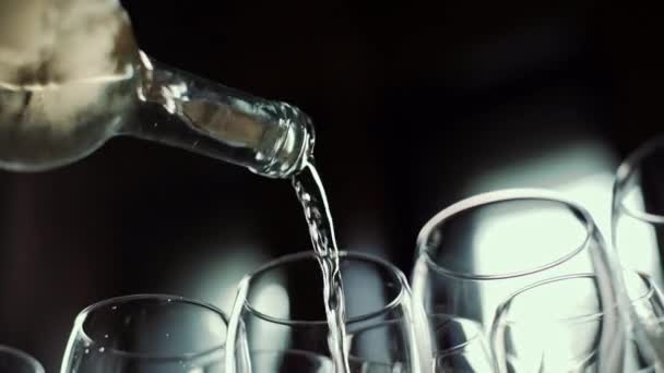 Close-up van een fles waaruit witte wijn in een doorzichtig glas wordt gegoten. — Stockvideo