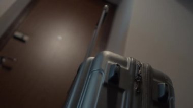 Adam tekerlekli bavulu alır ve evden dışarı çıkarır..