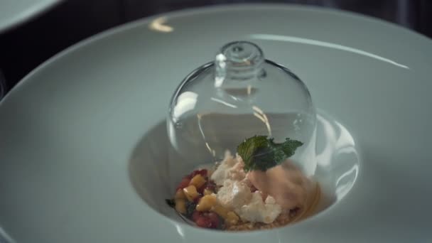 Een gastronomisch gerecht werd geserveerd op een wit bord onder een glazen deksel in een restaurant — Stockvideo