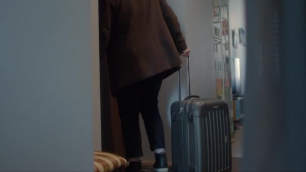 Homem pega uma mala sobre rodas e leva-a para fora da porta do apartamento. — Vídeo de Stock
