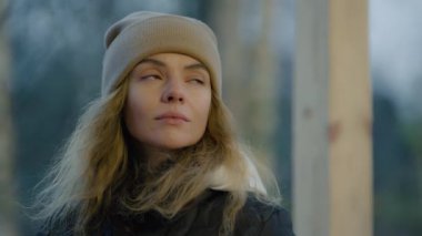 Soğuk bir sonbahar gününde fincandan sıcak çay içen ve etrafa bakan bir kadın. 