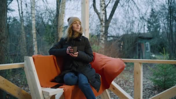 Vrouw met een wintermuts op een koude herfstdag, gepensioneerd en droevig rondkijkend — Stockvideo