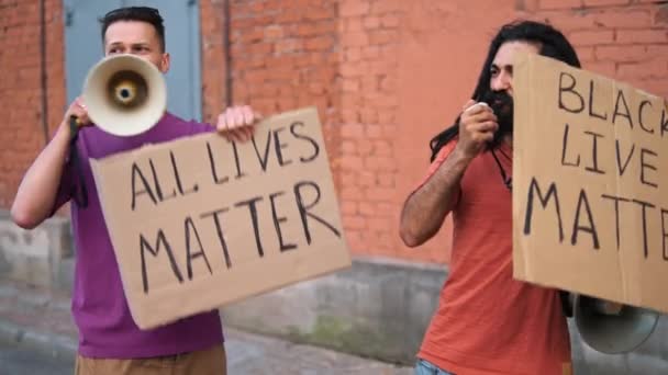 Dois homens caucasianos estão protestando na rua com megafones e sinais — Vídeo de Stock