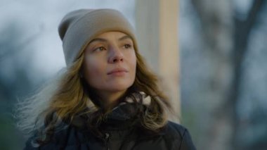 Soğuk bir sonbahar gününde fincandan sıcak çay içen ve etrafa bakan bir kadın. 