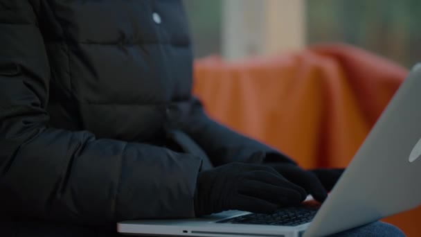 穿着紧身衣、头戴冬帽、头戴手套的特写镜头妇女在笔记本电脑上工作. — 图库视频影像