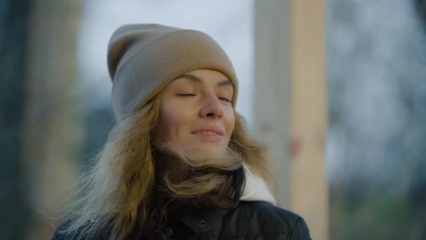 寒い秋の日の冬の帽子の女性は笑顔で、元気に周りを見回す. — ストック動画