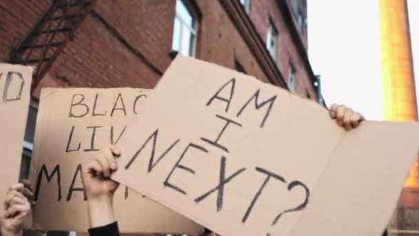 Протестующие на улице держат плакаты над головой — стоковое видео