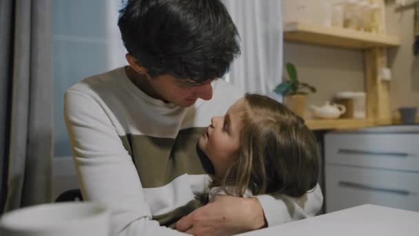 Маленькая девочка шепчет отцу на ухо. Любящий отец обнимает свою дочь — стоковое видео