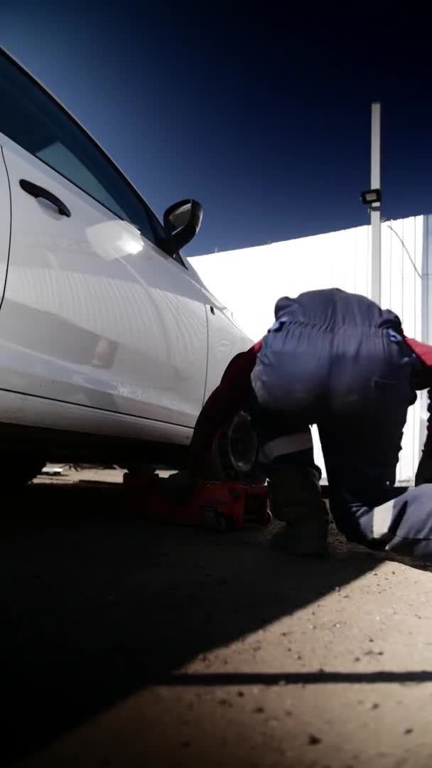 Guy meccanico auto in uniforme sostituisce pneumatico sulla ruota in servizio di riparazione auto. — Video Stock