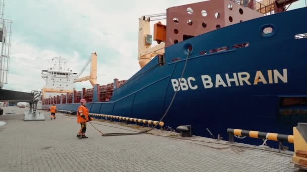 Ogromny statek z kontenerami ładunkowymi jest rozwiązywany z molo przez robotników. — Wideo stockowe