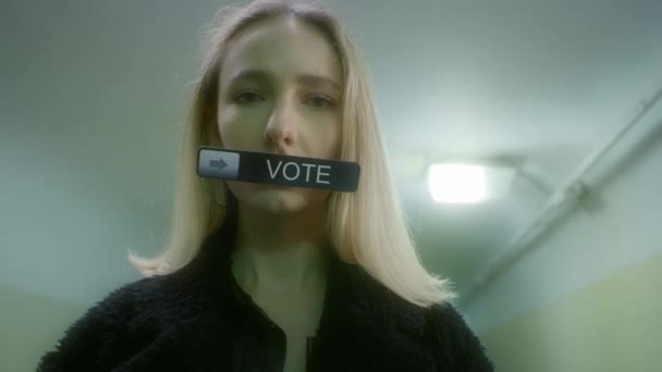 Женщина держит знак во рту с надписью - Голосуйте — стоковое видео
