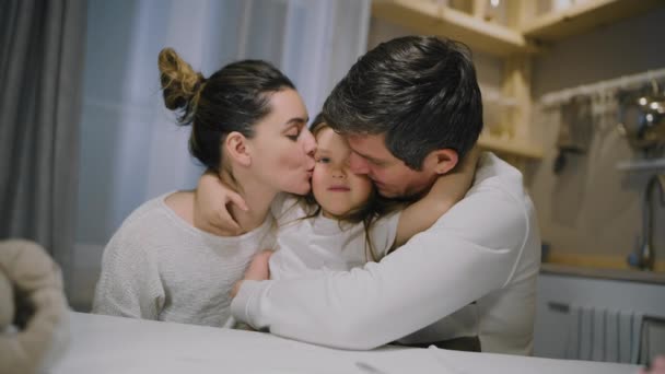 Familia papá mamá e hija abrazo en la mesa en la cocina. — Vídeo de stock