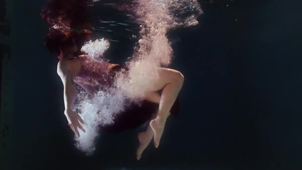 Жінка в купальнику і чорна спідниця плаває у воді, розмахуючи руками і ногами — стокове відео