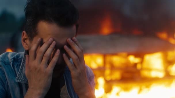 Homem agarra a cabeça, ele está muito chateado por causa do carro queimado no fogo. — Vídeo de Stock