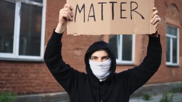 Muž v masce stojí s papírovým plakátem v ruce - BÍLÁ ŽIVÁ MATTER — Stock video