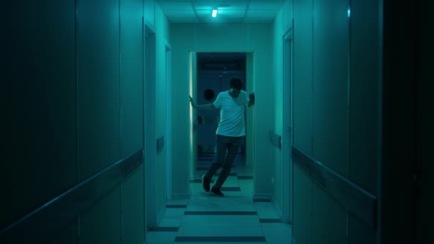 Людина з відсутністю координації руху йде по коридорах лікарні — стокове відео