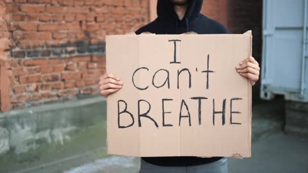 Hombre con máscara se para con cartel de cartón en las manos - I CANT BREATHE — Vídeo de stock
