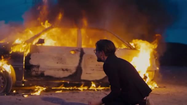 De mens is boos, knielend en schreeuwend door de verbrande auto.. — Stockvideo