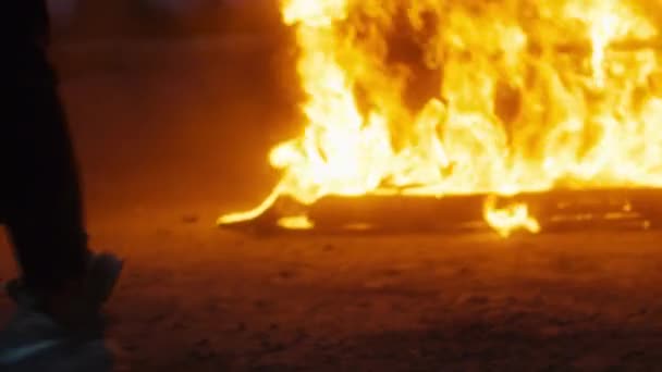 Man die danst een maanwandeling tegen de achtergrond van een brandende auto — Stockvideo