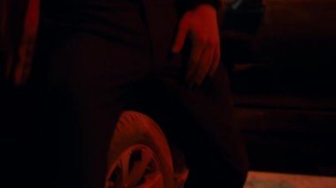 Güneş gözlüklü iki adam gece sokakta arabanın dışında güçlü bir şekilde dans ediyor.