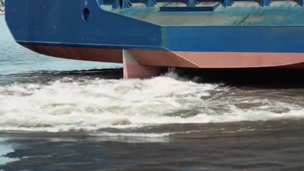 Buque de carga con contenedores navega lejos del muelle con una grúa y un puente. — Vídeos de Stock