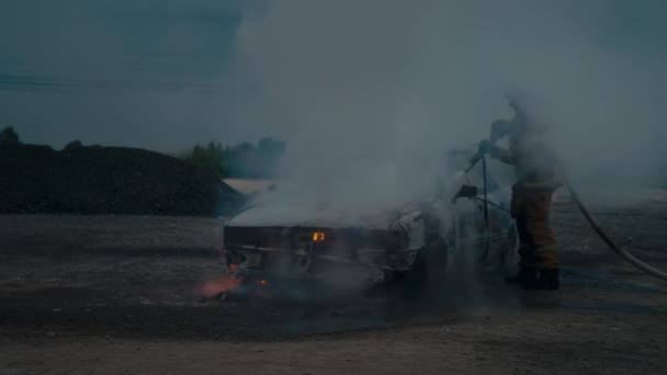 Bombero apaga un coche completamente quemado en la calle. Mucho humo.. — Vídeos de Stock