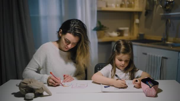 Matka a malá dcera kreslí kresby na papír v kuchyni se značkami — Stock video