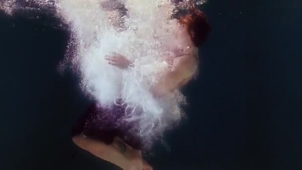 Mujer en traje de baño y falda negra nada en el agua, agitando brazos y piernas — Vídeo de stock