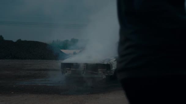 Brandweerman blust een volledig verbrande auto op straat uit. Heel veel rook.. — Stockvideo