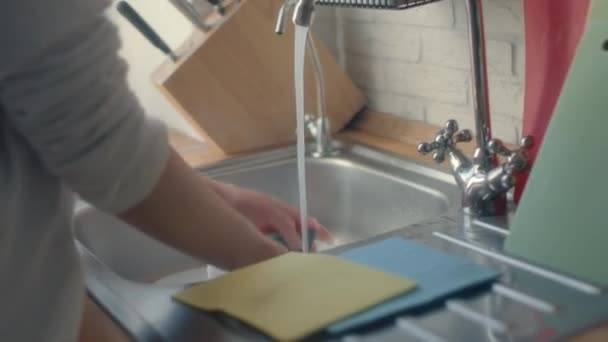 厨房里的女人在水龙头里的水流下洗一个白色的盘子. — 图库视频影像