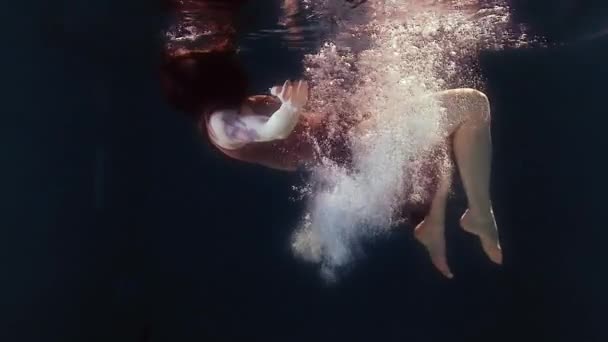 Vrouw in een badpak en een zwarte rok zwemt in het water, zwaaiende armen en benen — Stockvideo
