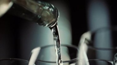 Beyaz şarabın şeffaf bir bardağa döküldüğü şişe.