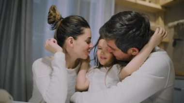 Aile babası, anne ve kızı mutfaktaki masada birbirlerine sarılıyorlar..