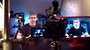 Gözlüklü blog yazarı video kameraya konuşuyor, lense odaklanmayı ayarlıyor