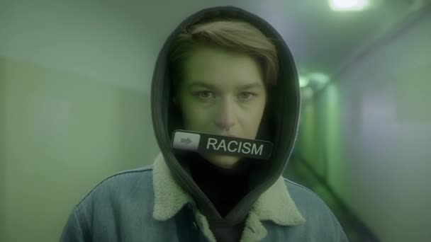 Femme à capuche et veste en denim tient un signe avec inscription - STOP RACISME — Video