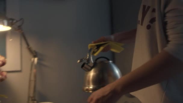 Woman in evening in kitchen pours hot boiled water from metal kettle into mug — Stock Video