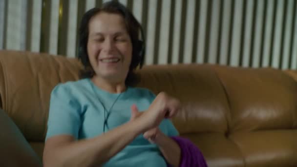 Mulher idosa em fones de ouvido e raios para danças de bordado incendiário à música — Vídeo de Stock