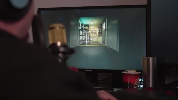 Человек в наушниках и с микрофоном играет в компьютерные игры по сети — стоковое видео