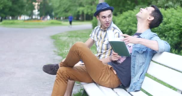 Deux gars sont assis sur un banc et parlent . — Video