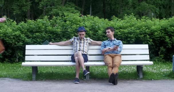 Deux gars sont assis sur un banc et parlent . — Video