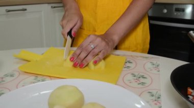 Kadın patates kesme tahtası üzerinde keser.