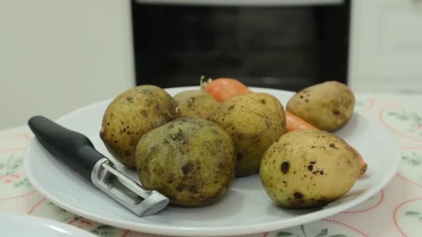 Неочищенные овощи на тарелке - картофель и морковь . — стоковое видео