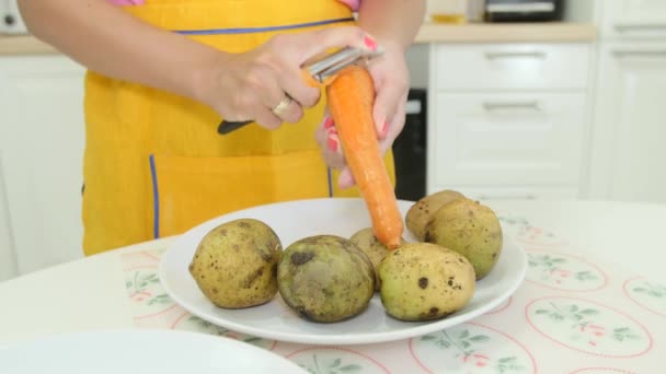 Eine Frau mit orangefarbener Maniküre, die eine Karotte schält — Stockvideo